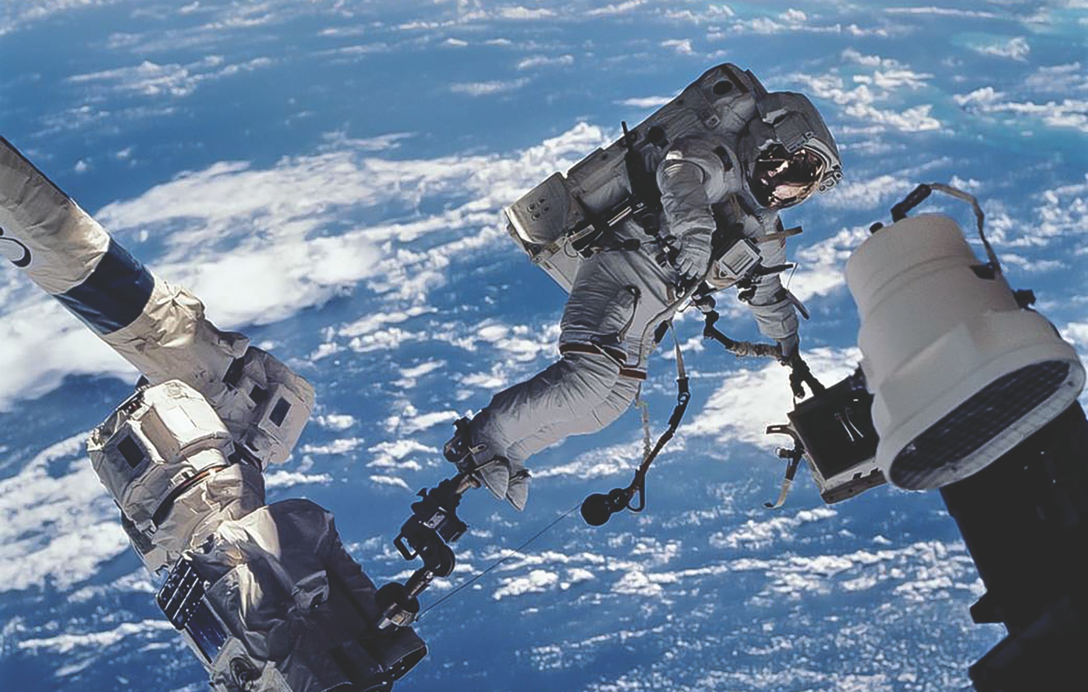Astronaut David A. Wolf, STS-112 mission specialist, anchored to a foot restraint on the Space Station Remote Manipulator System, carries the Starboard One outboard nadir external camera.