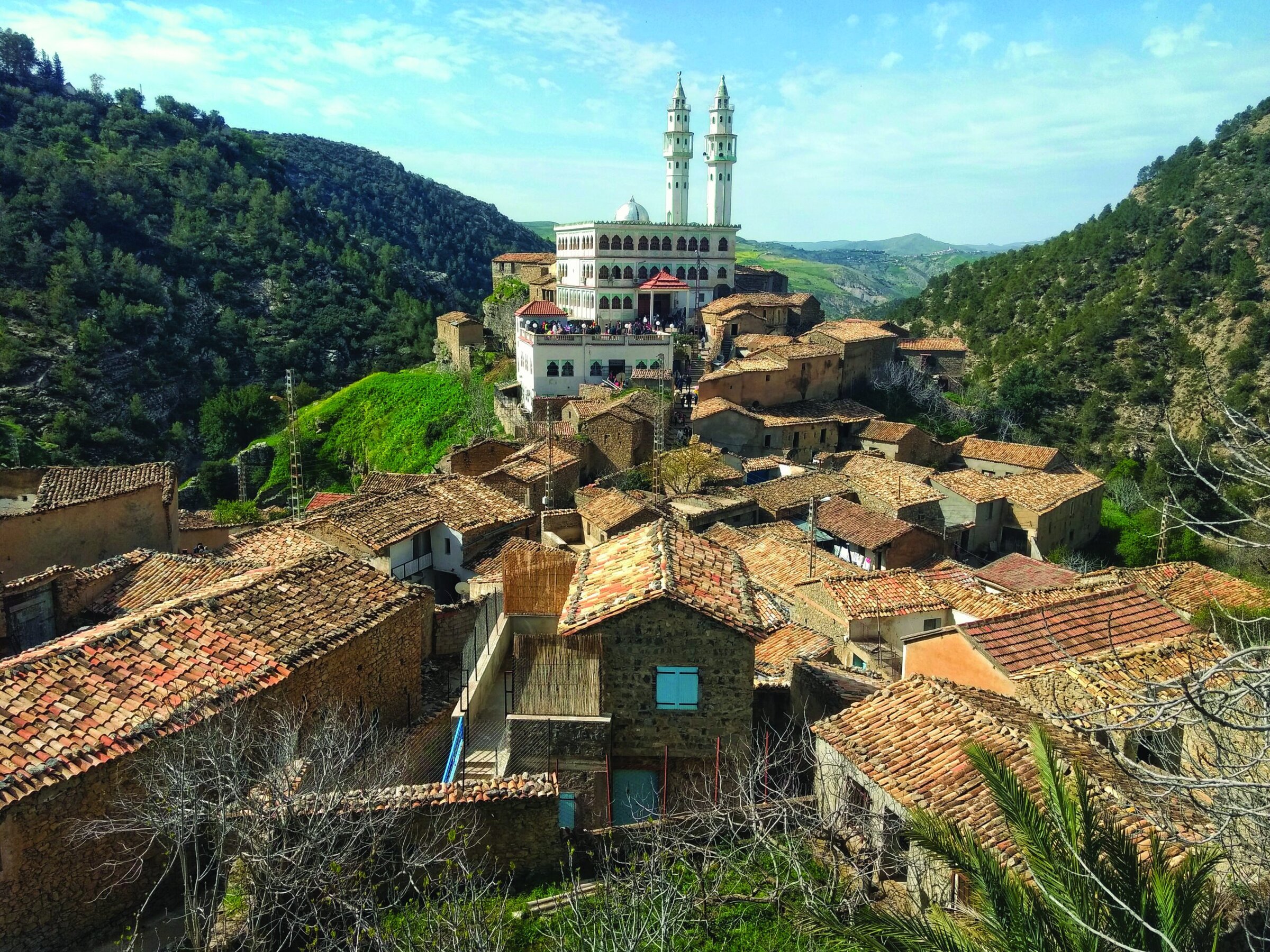 Colorful hillside village with ancient tiled roofs and a mosque, scenic view ideal for ceramics and pottery inspiration.
