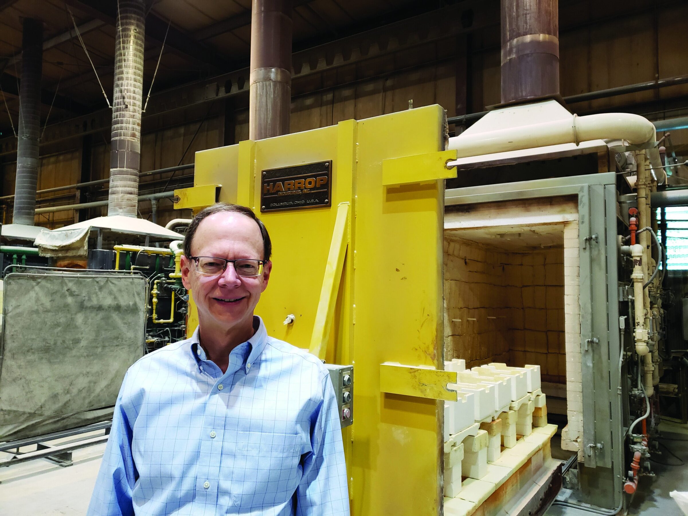 High-temperature industrial kiln used for ceramic and advanced material processing with a smiling man in front.