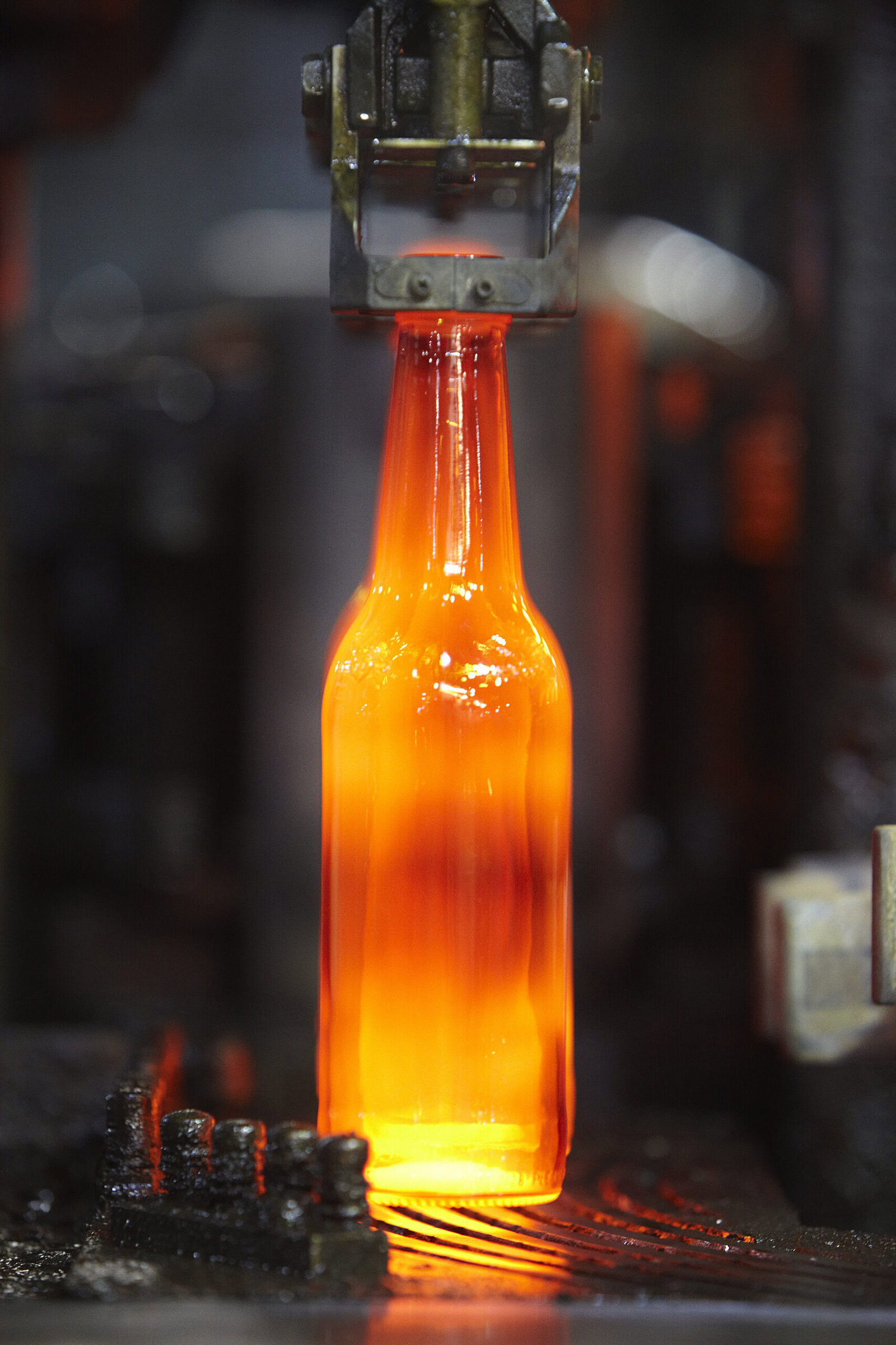 Hot glass bottle being shaped in glassblowing process at ceramics factory.