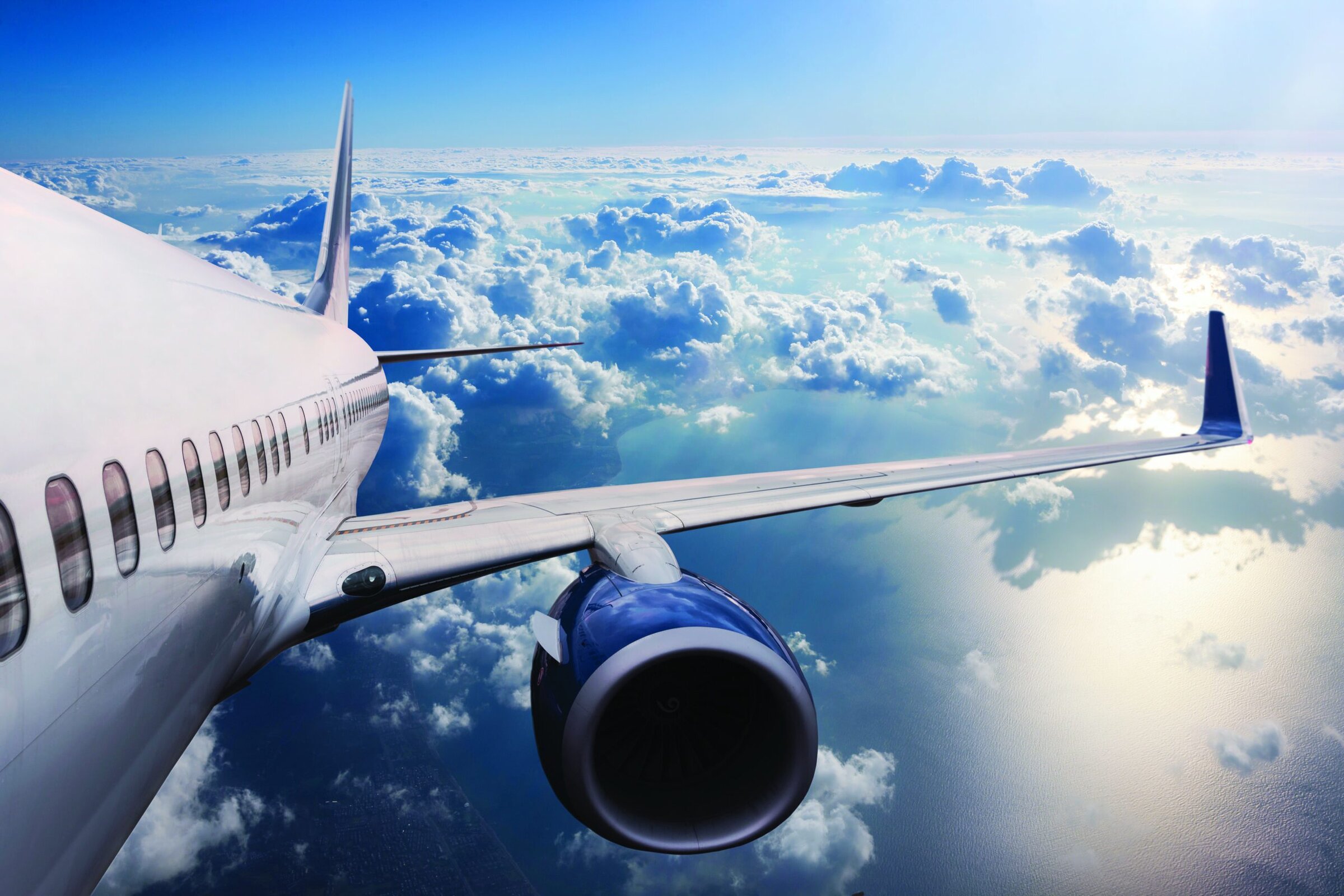 Aircraft flying above clouds in the sky, high-altitude view.