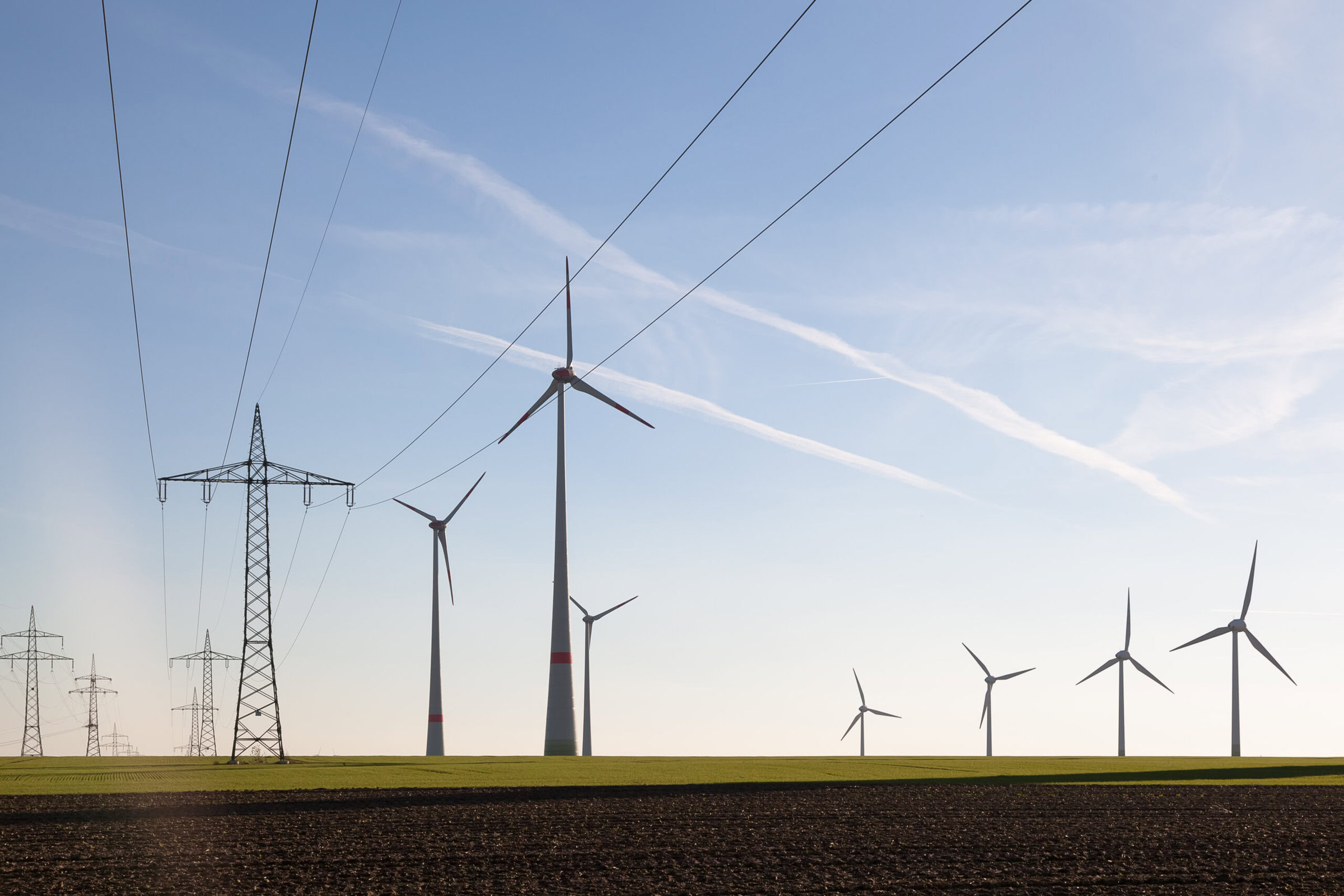 Wind turbines and power lines in a renewable energy wind farm for sustainable energy production.
