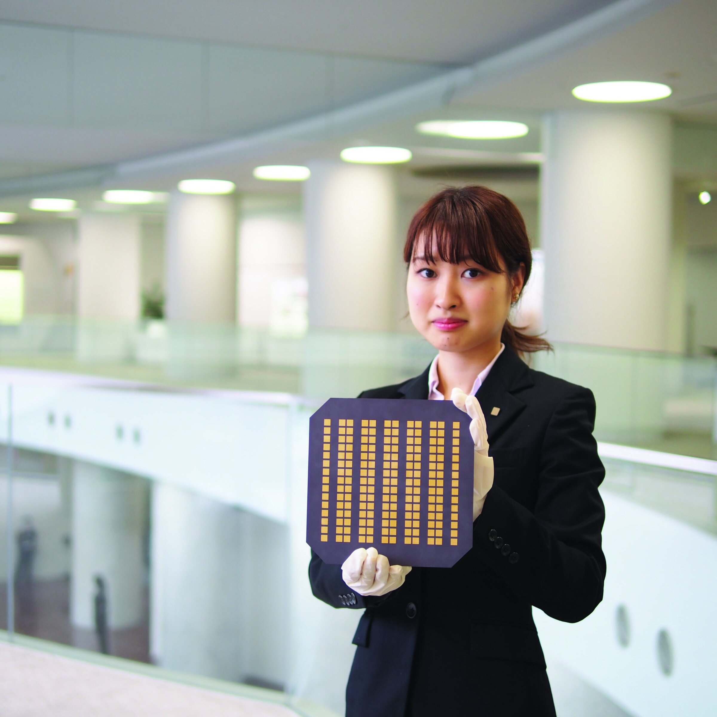 Silicon wafer for semiconductor manufacturing, held by a female scientist in a modern lab.