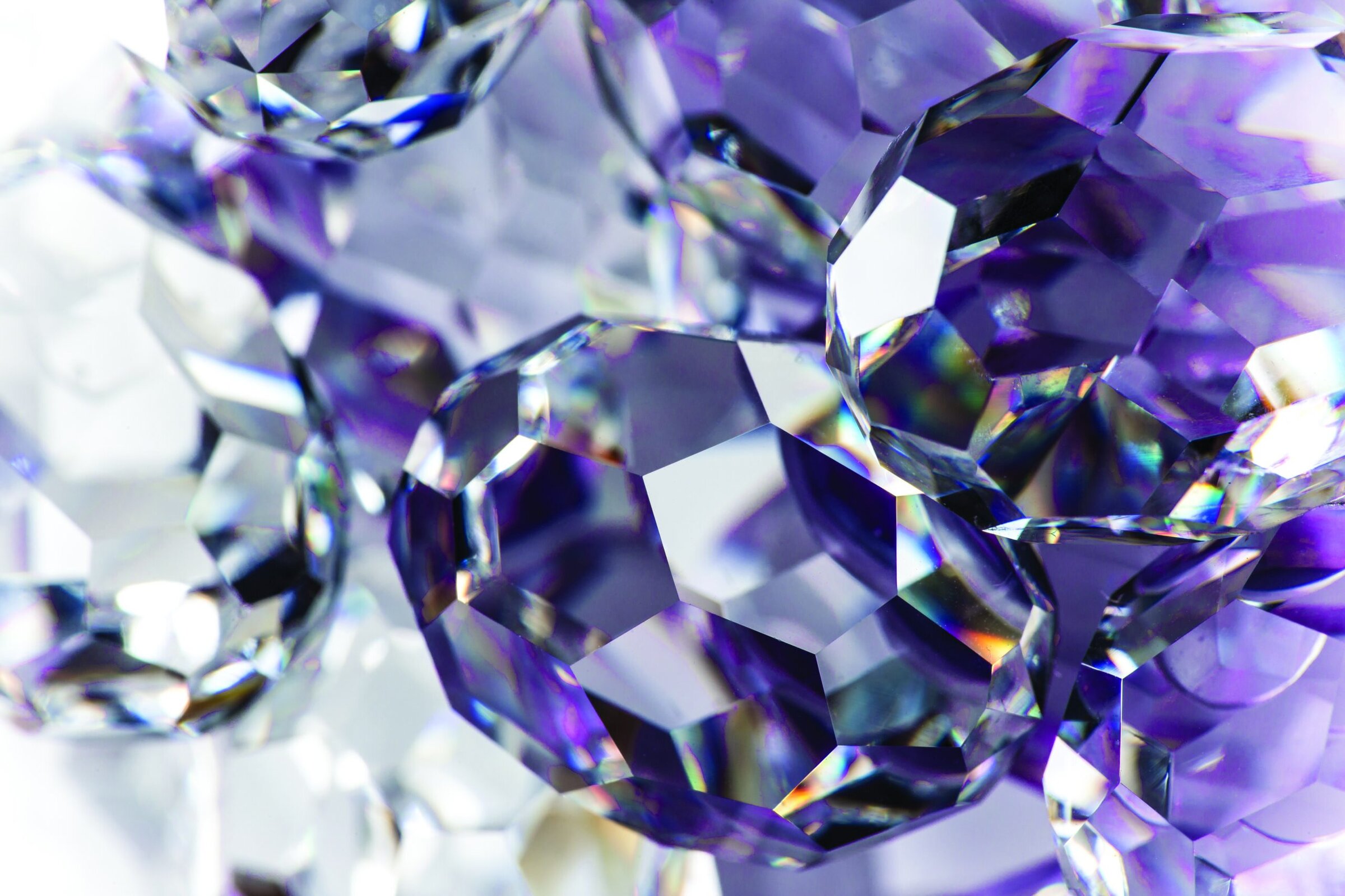 Sparkling crystal with purple and blue hues, showcasing cut facets and light reflections.