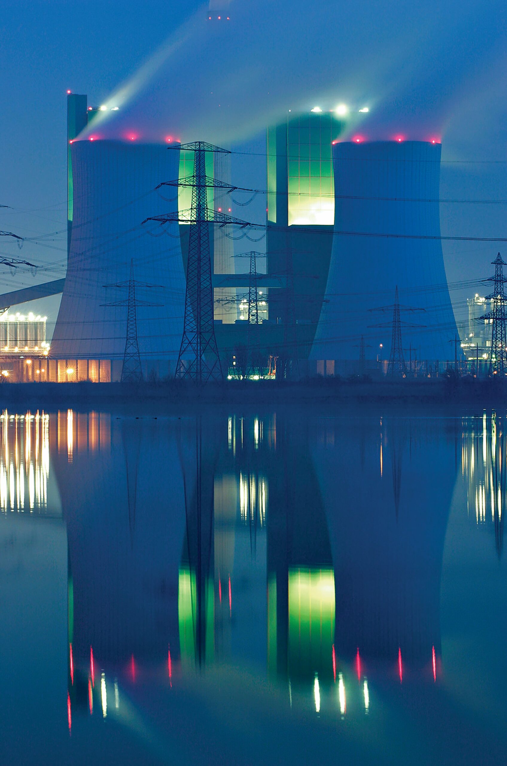 Power plant cooling towers emitting steam at night.