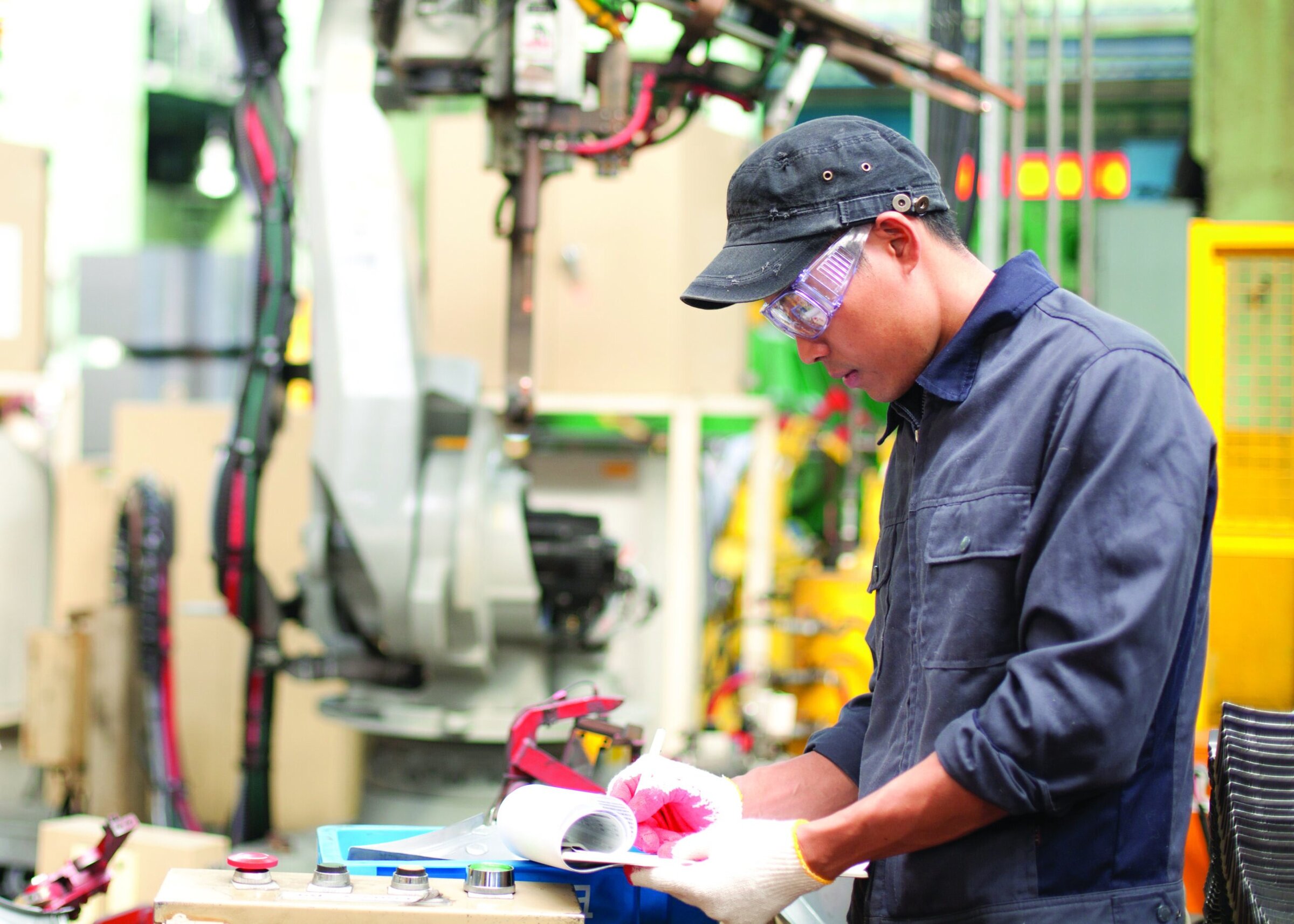 Ceramics manufacturing technician working in an industrial ceramics facility, inspecting materials, with high-tech equipment in the background.
