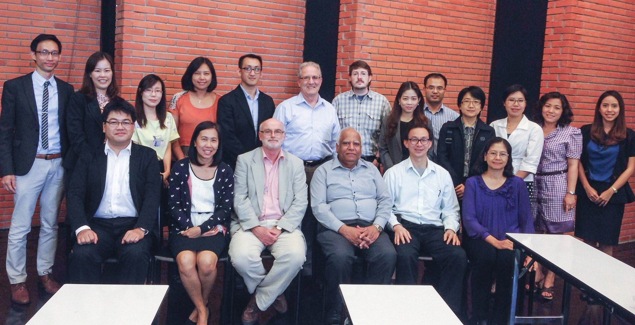 Group of international professionals attending a ceramics industry conference or seminar, standing against a brick wall.