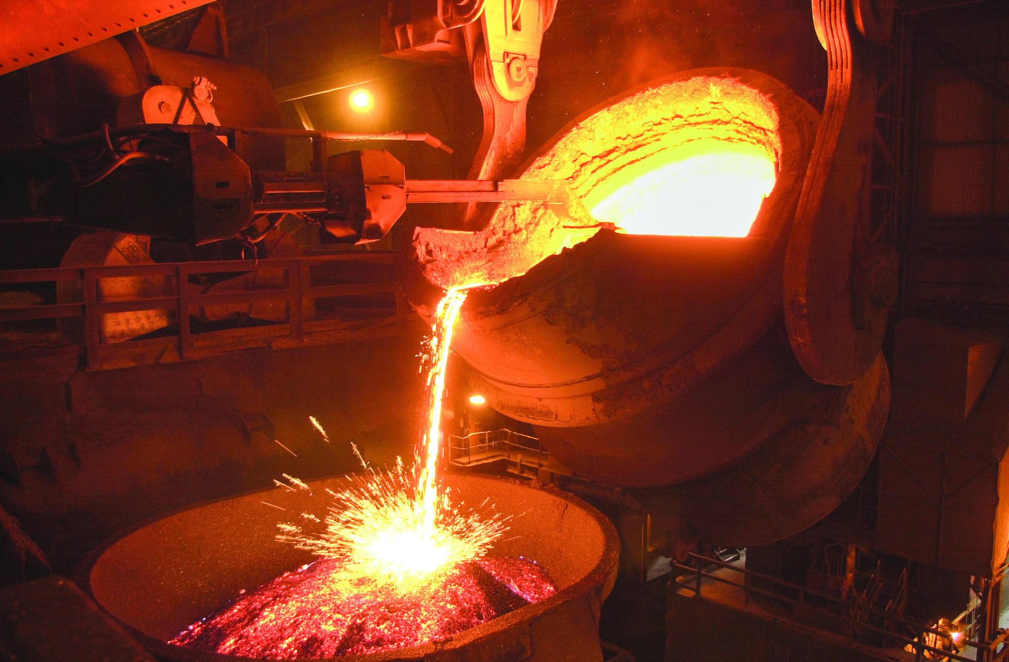 Molten metal pouring into a large container during steel manufacturing process.