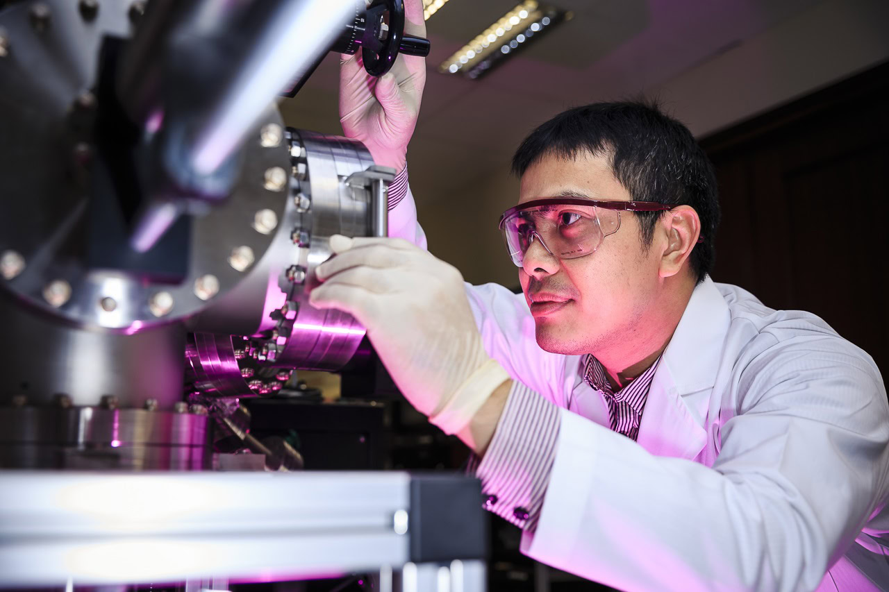 A scientist in safety glasses and lab coat examining high-tech ceramic components in a research facility.