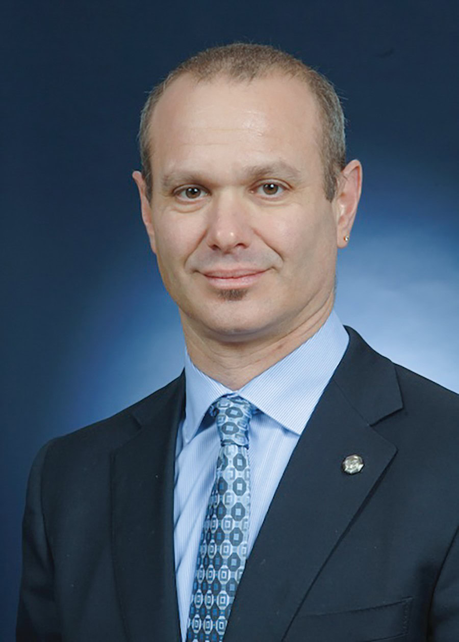 James A. Warren smiling against a blue background