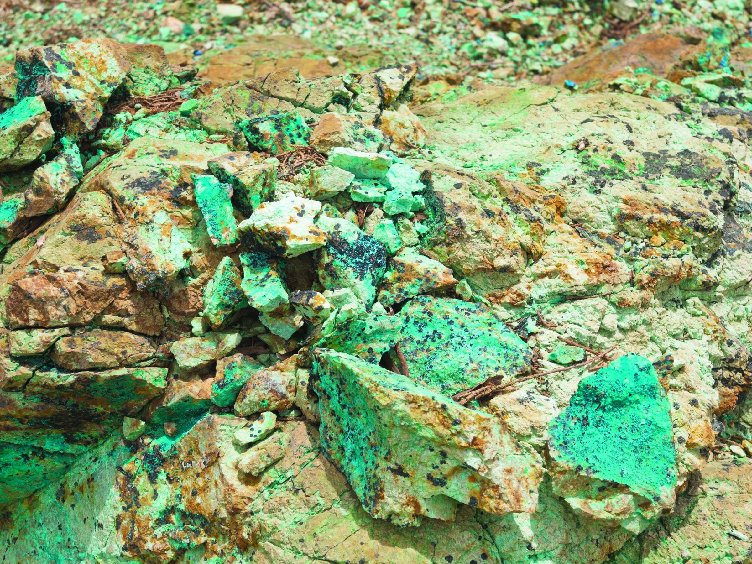 Bright green copper oxidation on rocks, showcasing minerals and natural ceramic-like textures.