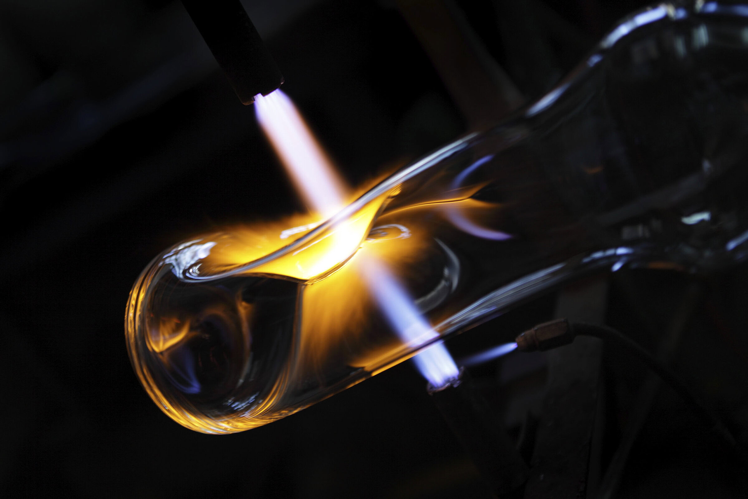 Molten glass being shaped with a torch for ceramic and glass art.