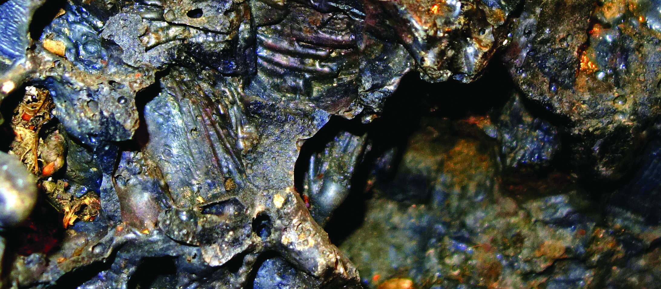 Shiny black volcanic rocks with iridescent hues and textured surfaces, ideal for ceramic and glaze applications.