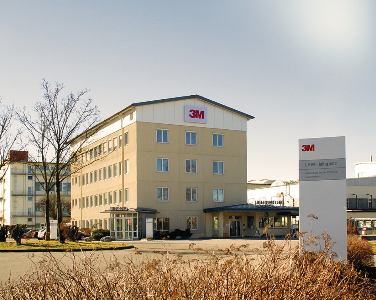 Modern office building with 3M logo in an industrial park, featuring beige walls and multiple windows.