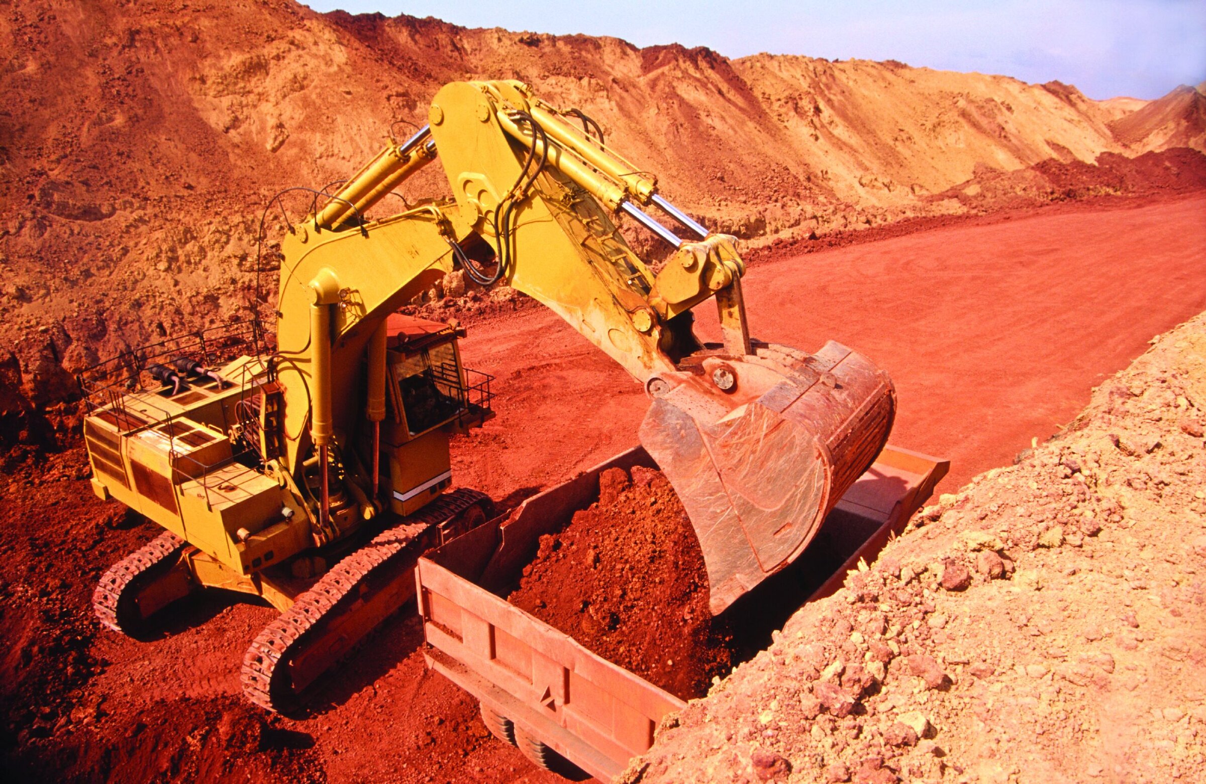 Heavy construction excavator working on desert-like terrain, mining or earthmoving process for ceramic raw materials.