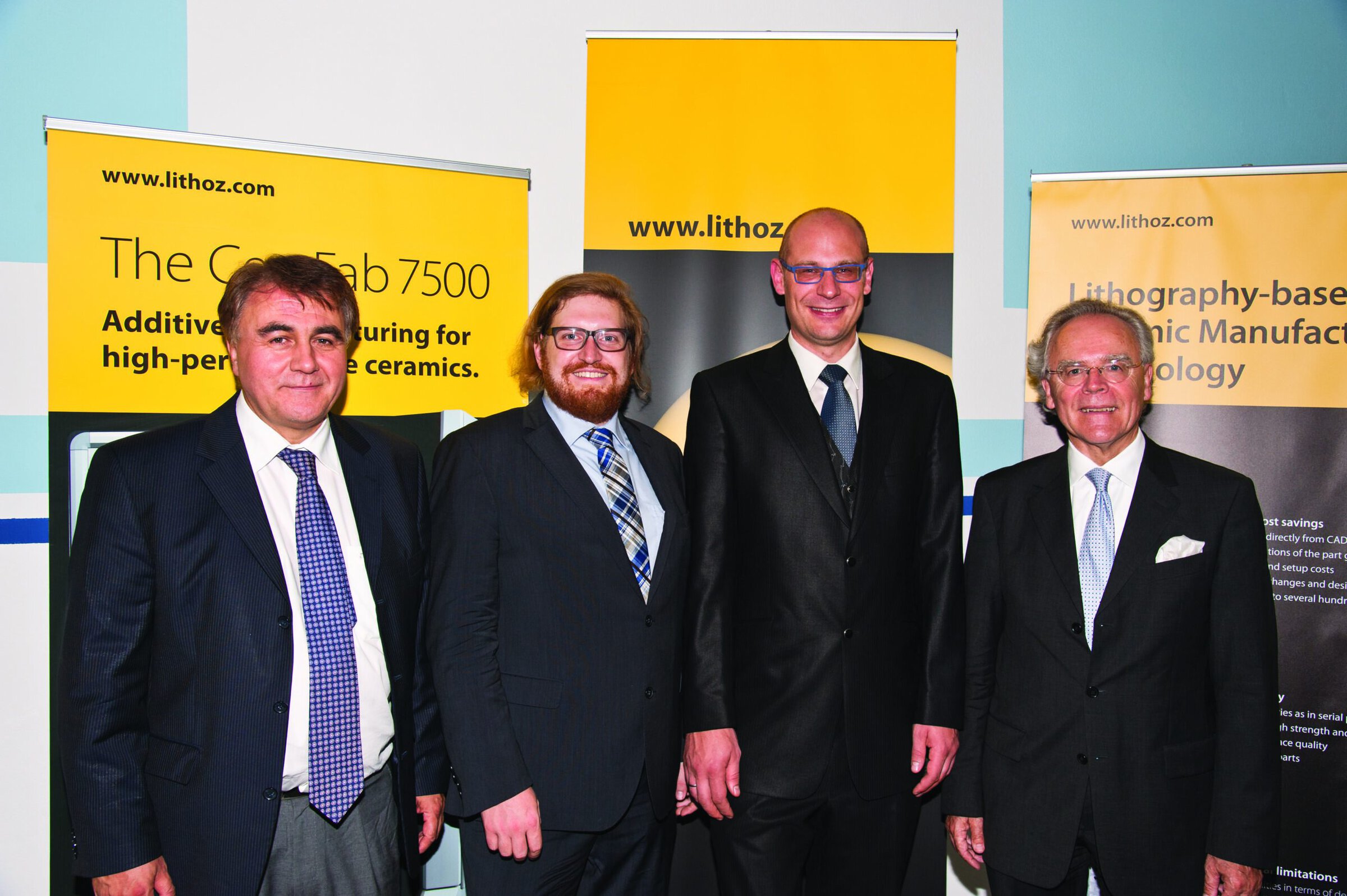 Lithography and ceramics experts at conference with Lithoz banners in background.