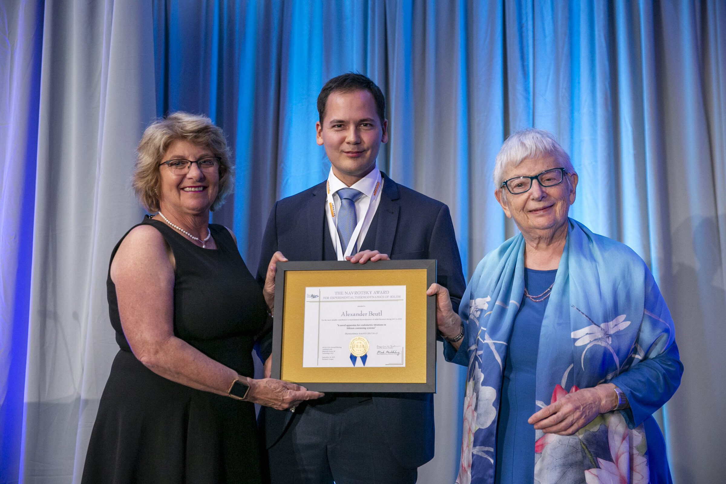 Award presentation at Ceramics conference with recipients holding framed certificate, celebrating excellence in ceramics research.