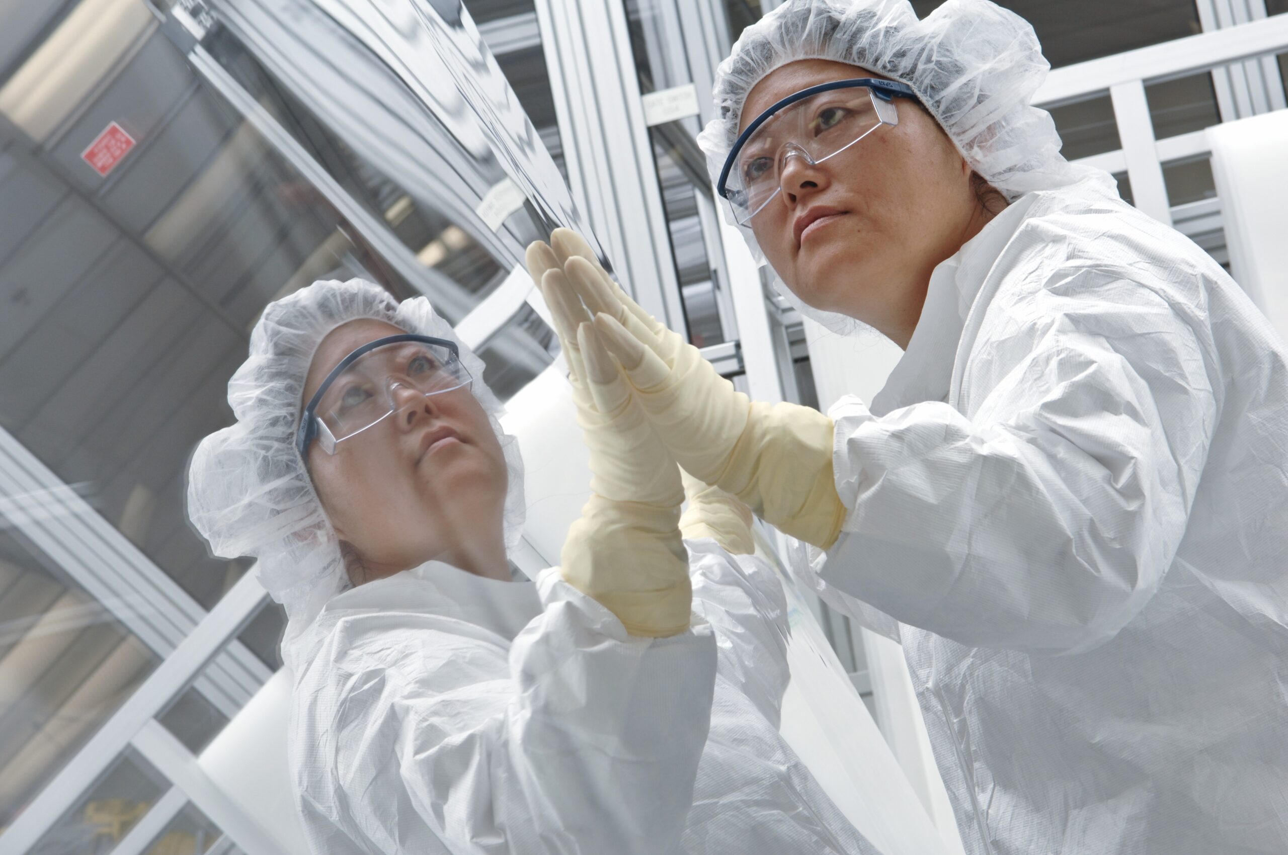 High-tech ceramics research professionals in cleanroom, wearing protective gear and examining materials.