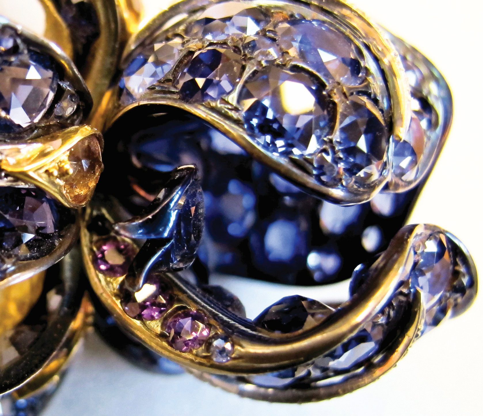 Twisted jewelry with clear and purple gemstones, gold setting, close-up.