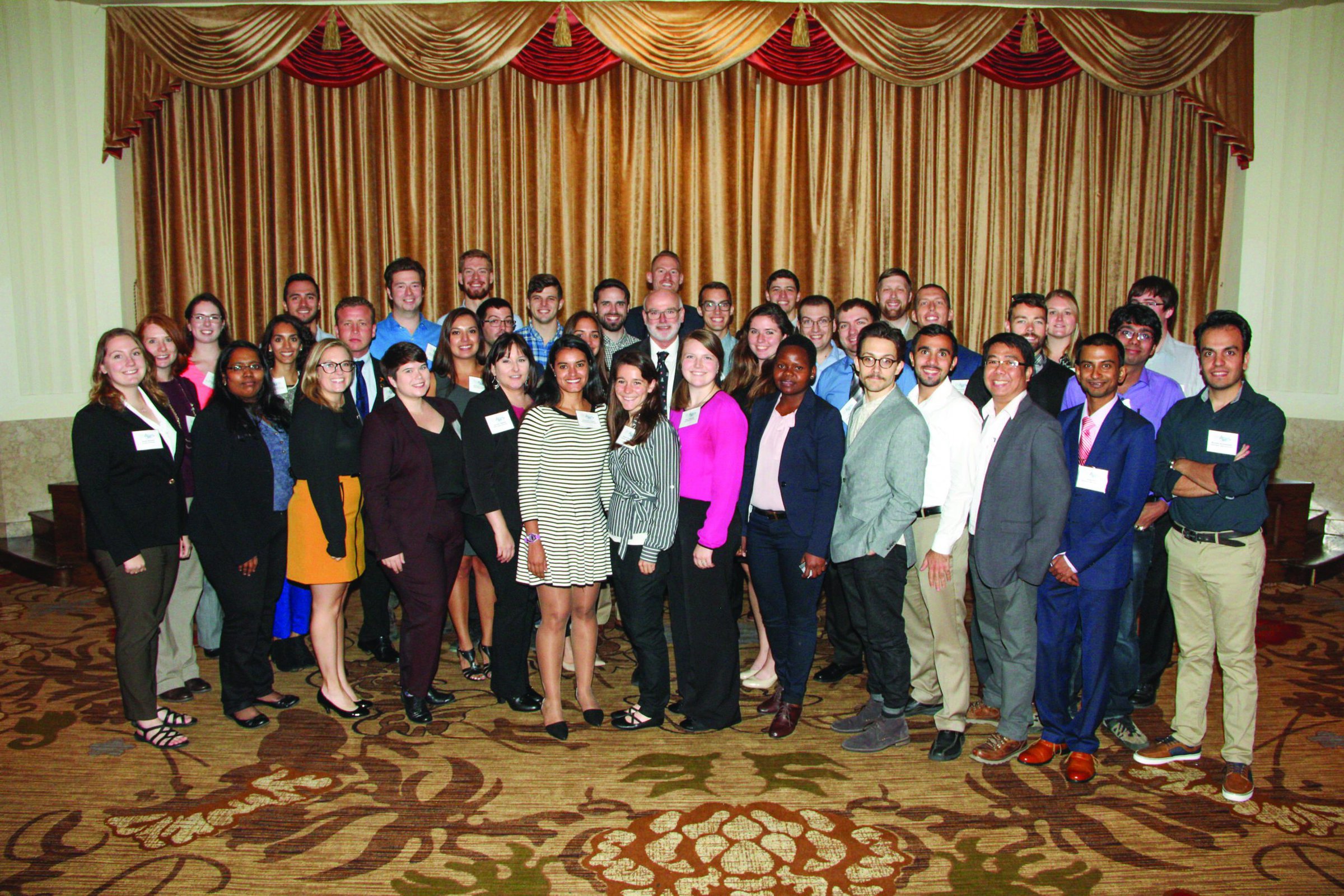 Group of professionals at ceramics industry conference, ACerS Bulletin event, in a formal setting.