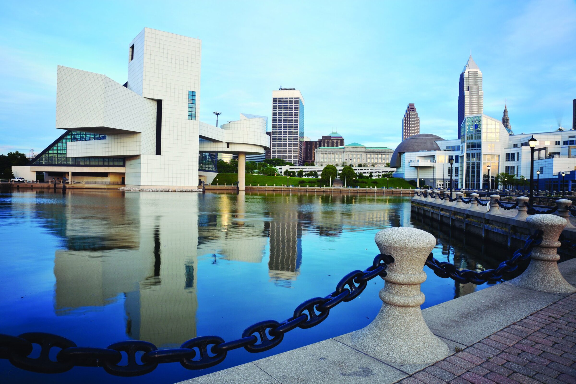 Modern Cleveland Museum of Art building reflected in the water, with Cleveland skyline in the background.