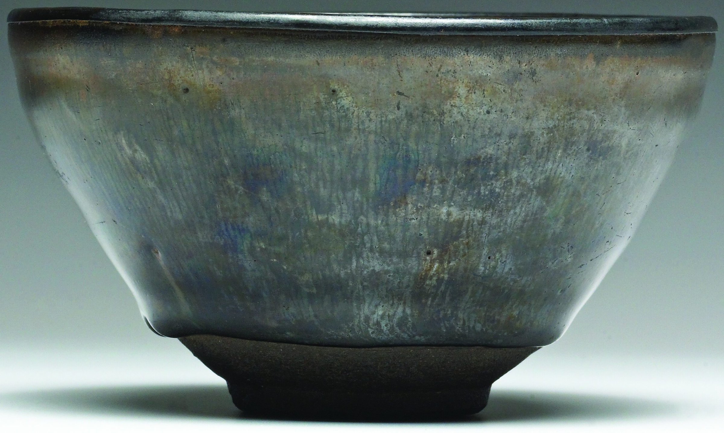 Intricate ceramic bowl with iridescent glaze reflecting ceramic art craftsmanship.