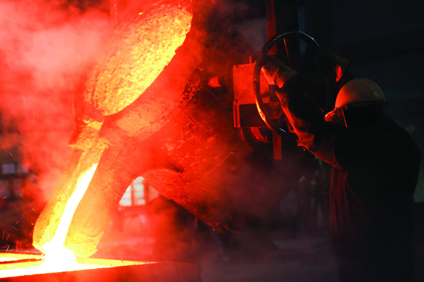 Molten metal being poured in a foundry with intense orange glow and sparks flying, showcasing high-temperature metalworking.