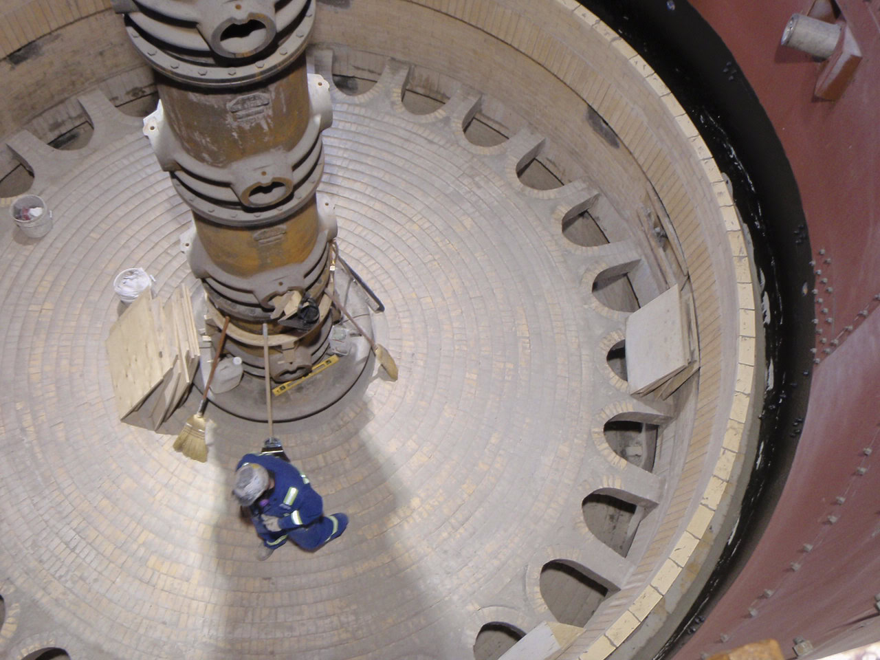 Precise ceramic tile installation around a large industrial machine in a controlled environment.