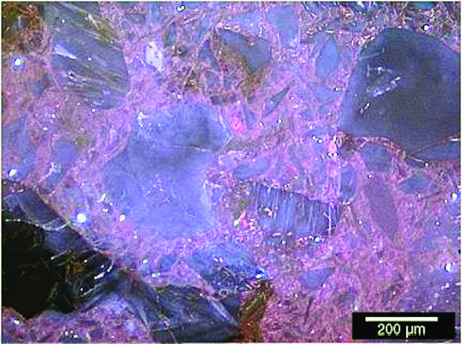 Colorful mineral microstructure with purple, blue, and black crystalline formations, magnified to reveal fine details at 200 µm scale.