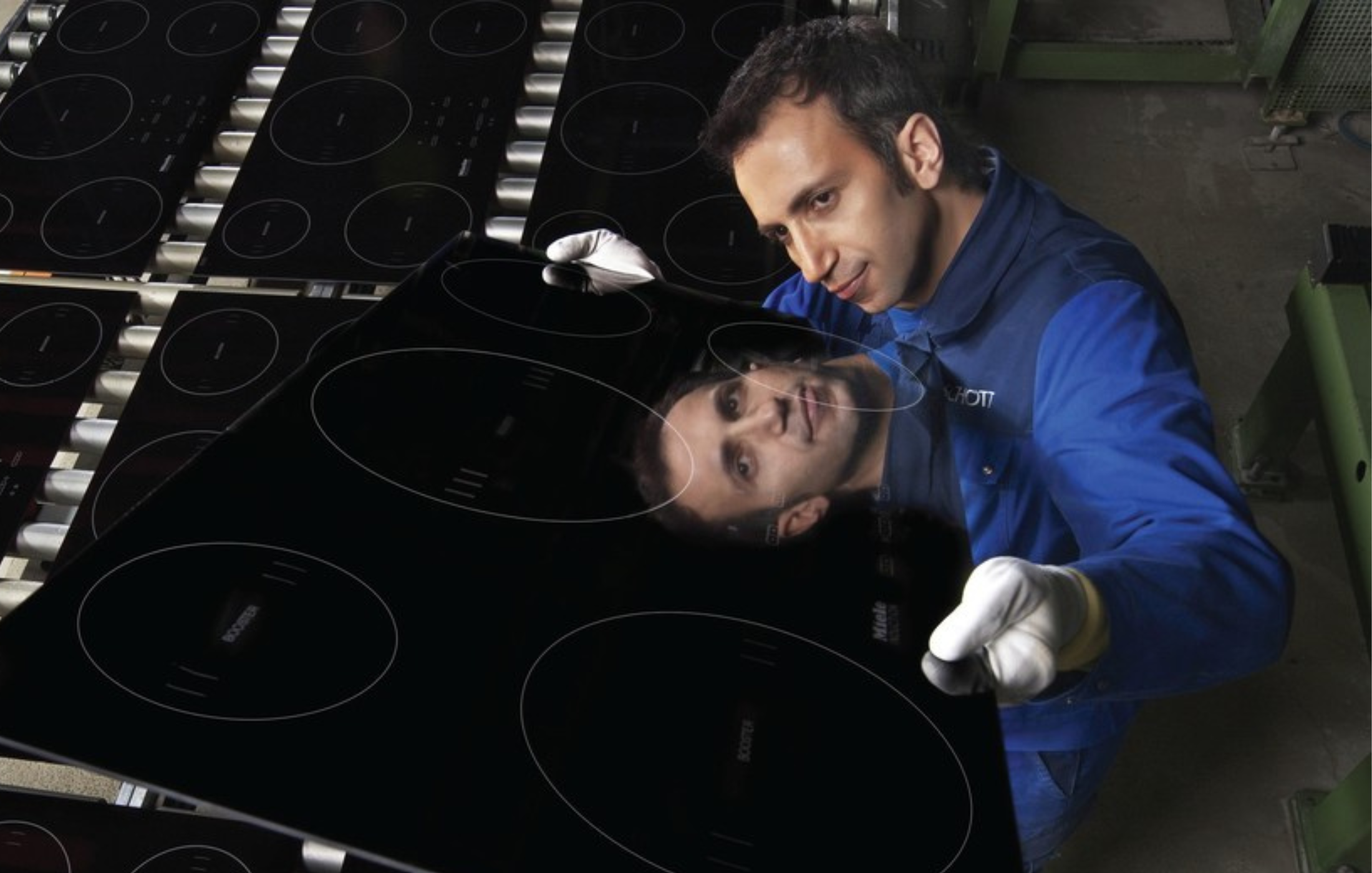 A technician inspects a glass-ceramic cooktop in a laboratory setting.