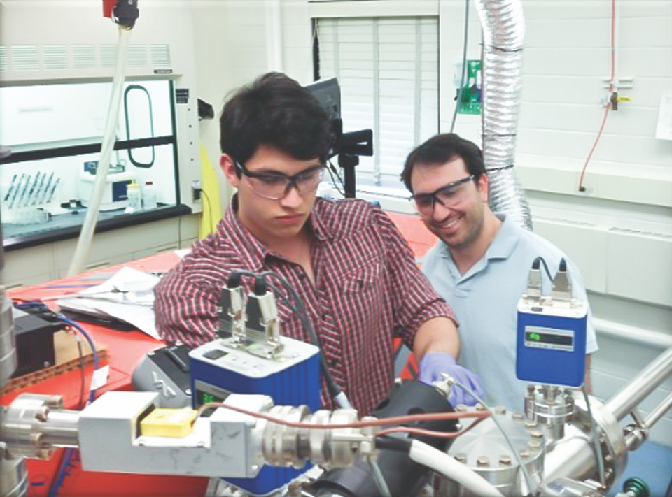 A young man and an older man working together on a scientific experiment in a laboratory.