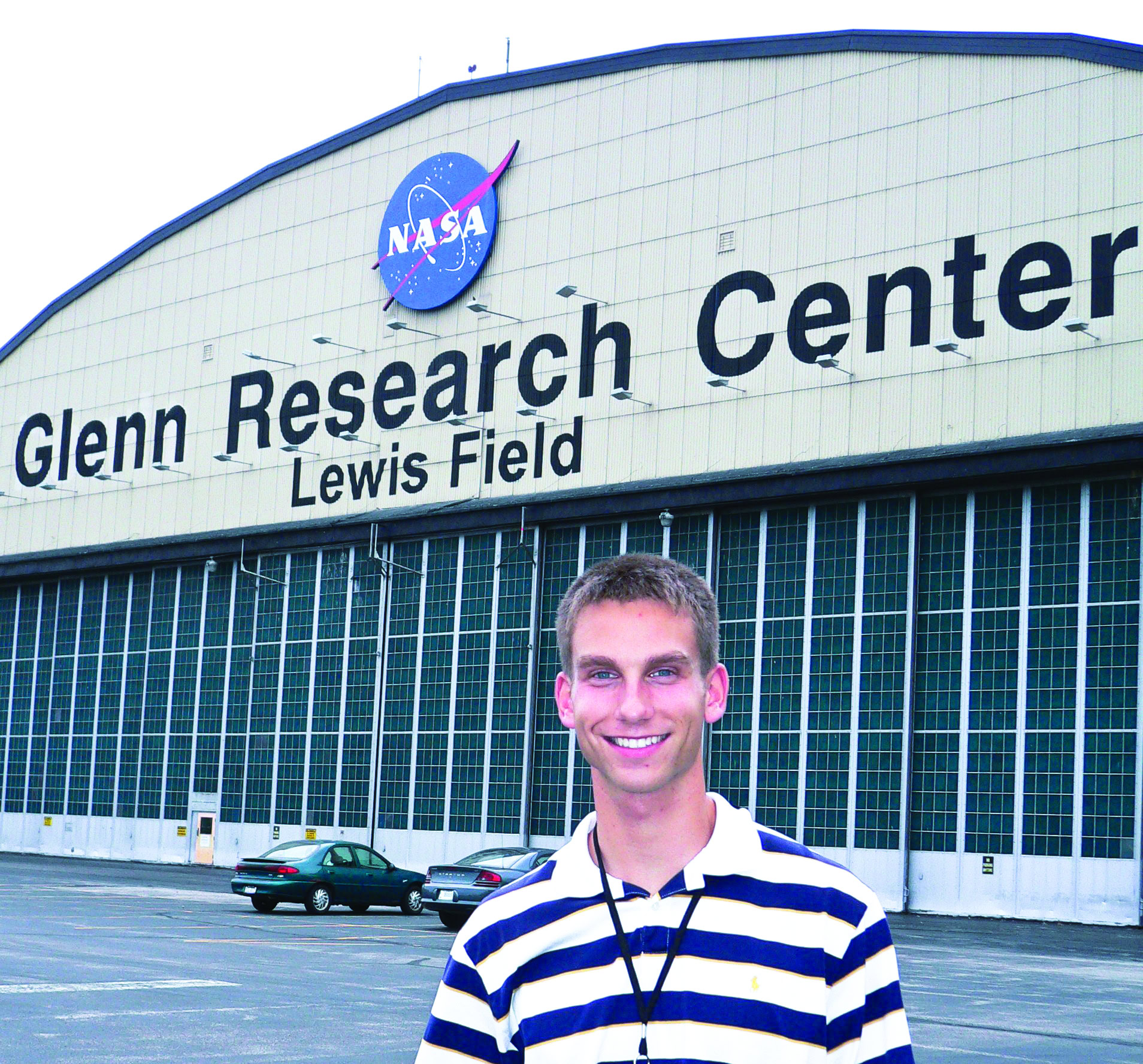 NASA Glenn Research Center building with a smiling young man in front, outside Lewis Field.